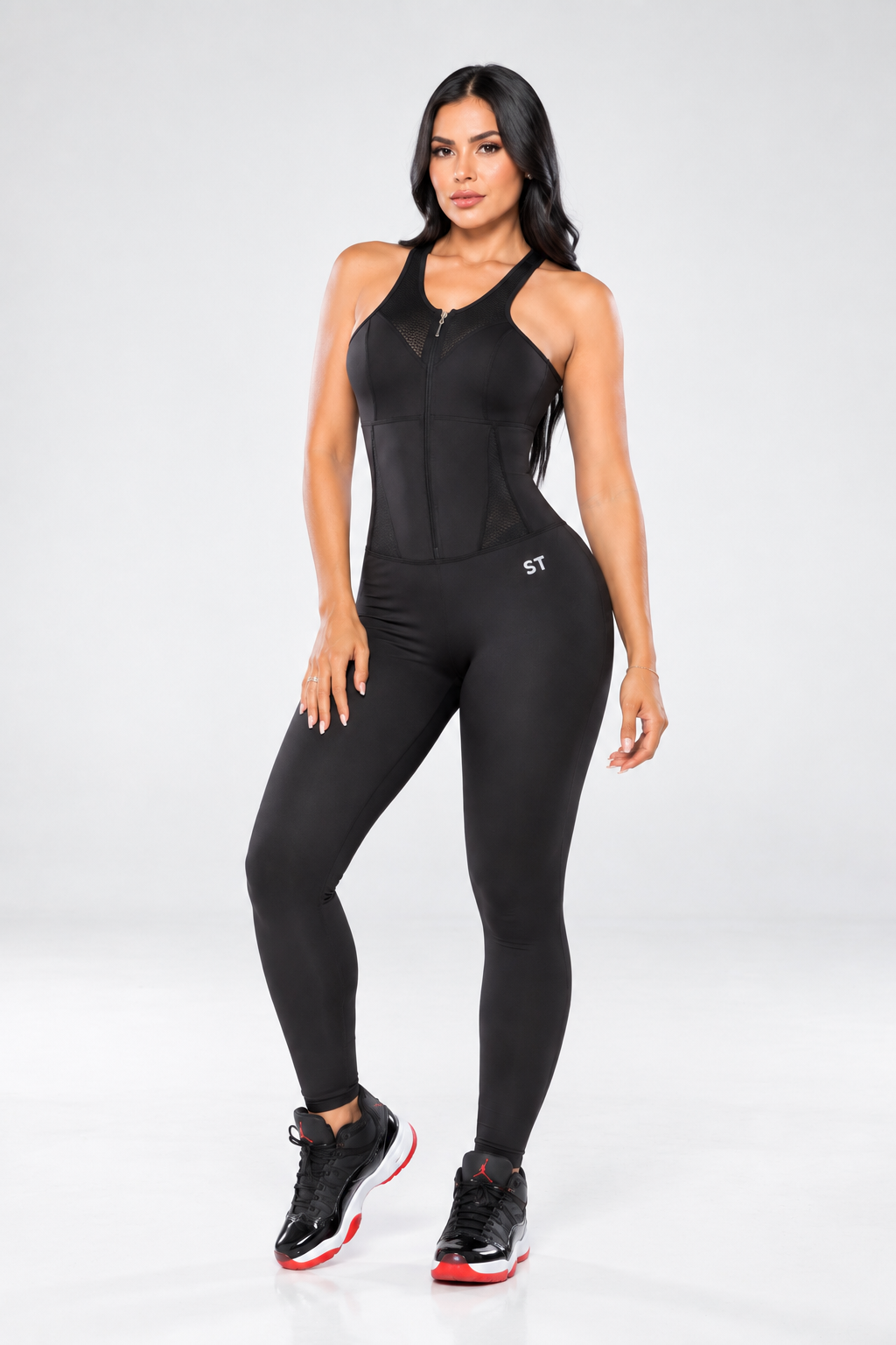 Modelo latina luciendo enterizo deportivo negro STAGMI, vista posterior, con ajuste estilizado y diseño racerback.